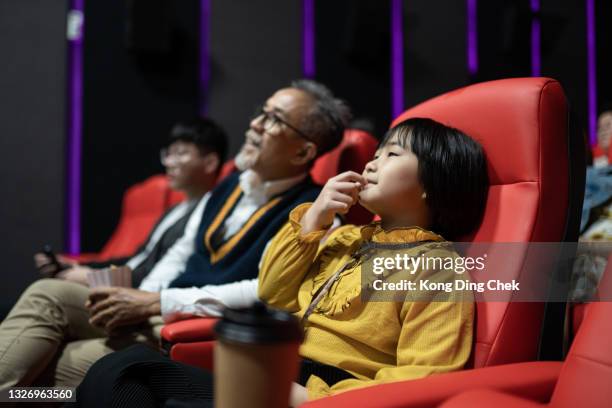 asiatischer chinesischer großvater mit seinen enkelkindern im kino, der popcorn isst und einen film sieht - film gala inside stock-fotos und bilder