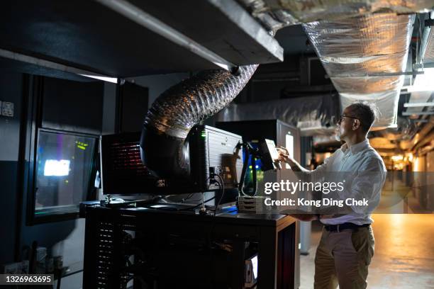 sistema operativo chino asiático del trabajador mayor del hombre en la sala moderna de la proyección de la película - operational technology fotografías e imágenes de stock