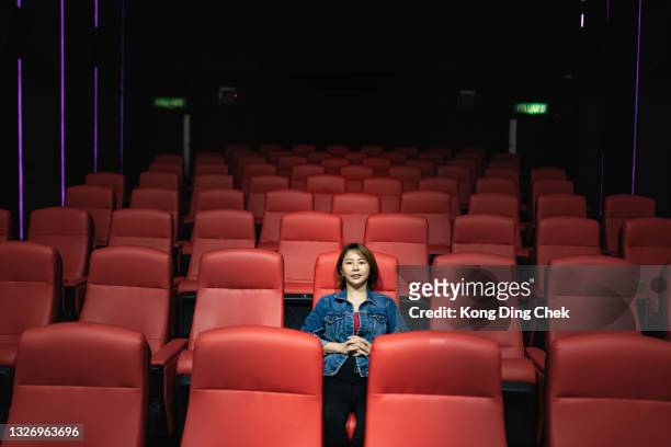 asian chinese woman alone in cinema watching movie - silhouette auditorium stock pictures, royalty-free photos & images