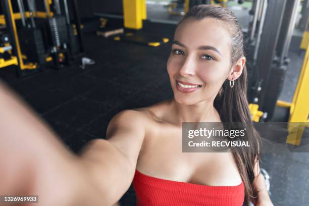 portrait of a smiling woman taking a selfie on her cell phone at the gym - gym reopening stock pictures, royalty-free photos & images