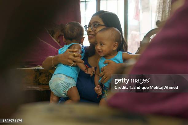 indian mother  playing with her young non identical twin boys. - twins stock pictures, royalty-free photos & images