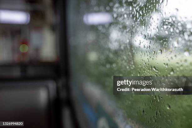 close-up and macro view of raining water drop on outside windows of the tram or train and defocused background of indoor passenger train. - humidity stock pictures, royalty-free photos & images