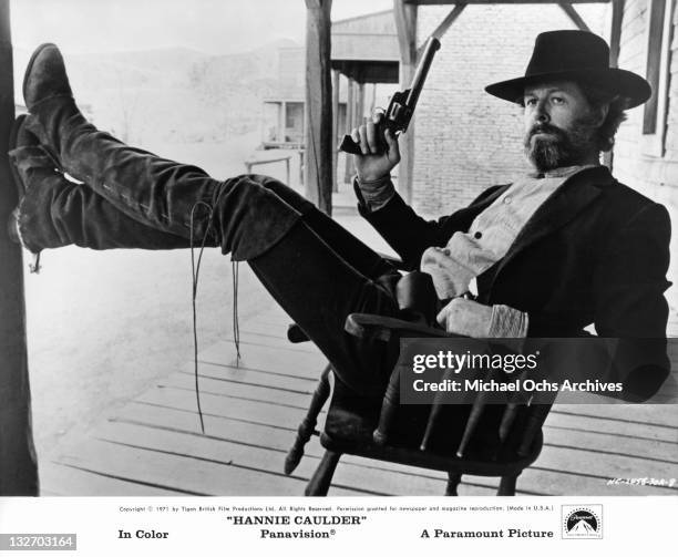 Robert Culp reclining with pistol in hand in a scene from the film 'Hannie Caulder', 1971.
