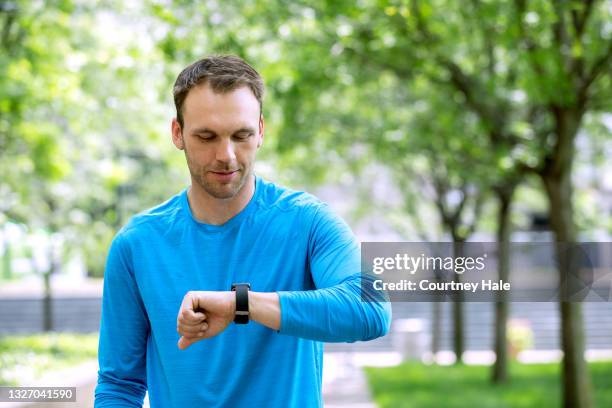 mann joggt im stadtpark und überprüft smartwatch - pedometer stock-fotos und bilder