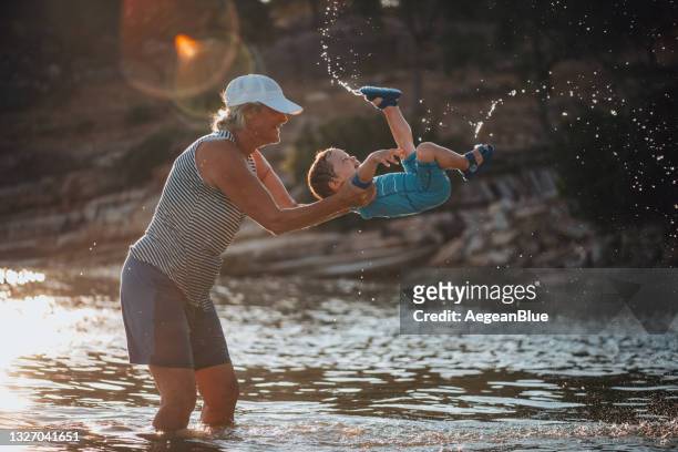 baby boy playing with his grandmother in the sea - family time stock pictures, royalty-free photos & images