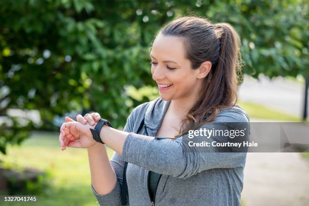 woman checks her smart watch after going for a jog in city park - pedometer stock pictures, royalty-free photos & images