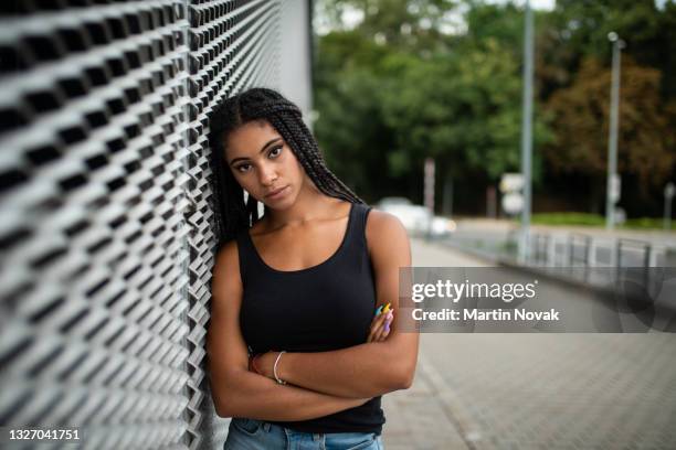 teenage model posing while leaning against mesh wall - black teenage girl stock pictures, royalty-free photos & images