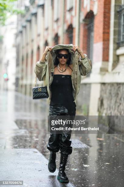 Hera Pradel wears black sunglasses, silver earrings, a white and silver pearls necklace, a black tank-top from Off-White, a gold shiny leather...