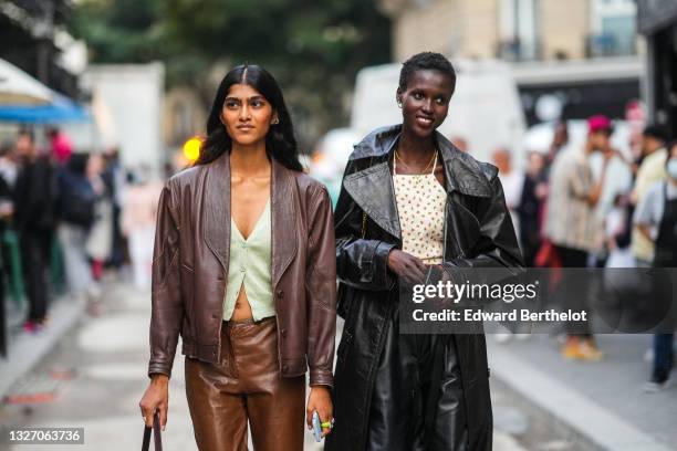 Model wears a pale green ribbed buttoned cardigan, a dark brown shiny leather blazer jacket, brown shiny leather flared pants, neon green / silver /...