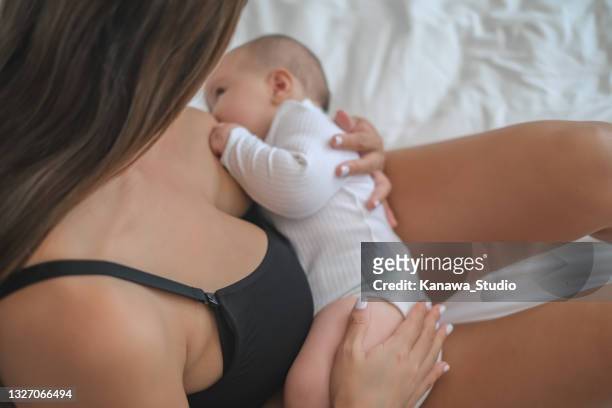 new mom breastfeeding her newborn baby in bed - girls in bras photos 個照片及圖片檔