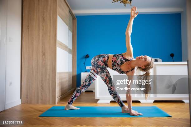 woman doing yoga at home, assuming revolved triangle pose - revolved triangle pose stock pictures, royalty-free photos & images