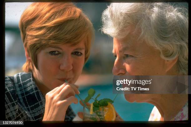 Singer Cilla Black and actress Gracie Fields sharing a drink, circa 1968.