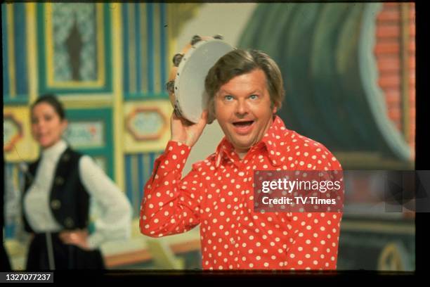 Comedian Benny Hill performing with a tambourine on set, circa 1971.