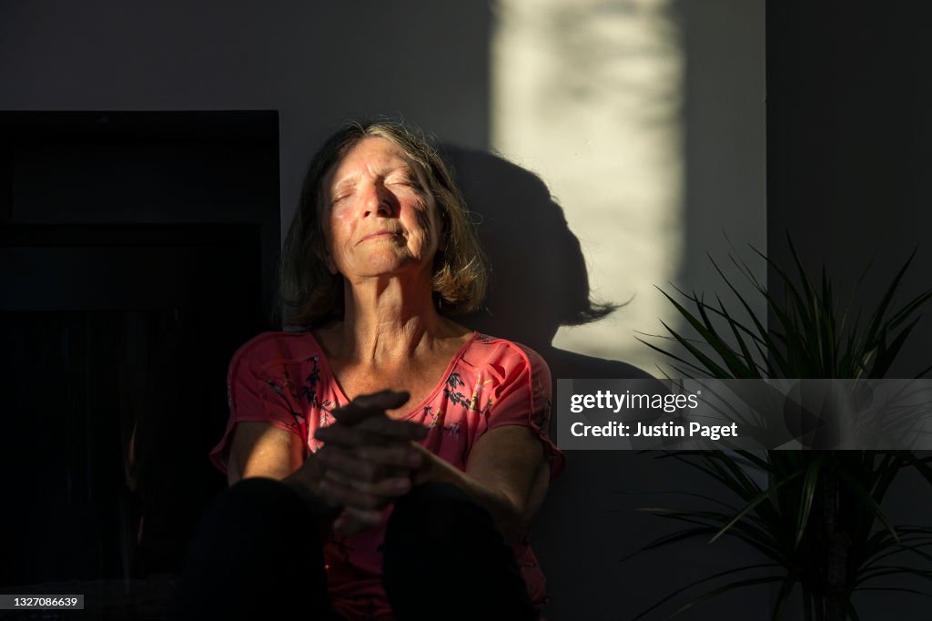 Senior lady catching the last of the sun's rays in her home