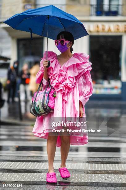 Guest wears a pale pink oversized ruffled long puffy sleeves knees dress, pink Gucci sunglasses, a fuchsia pink shiny leather hand bag with an...