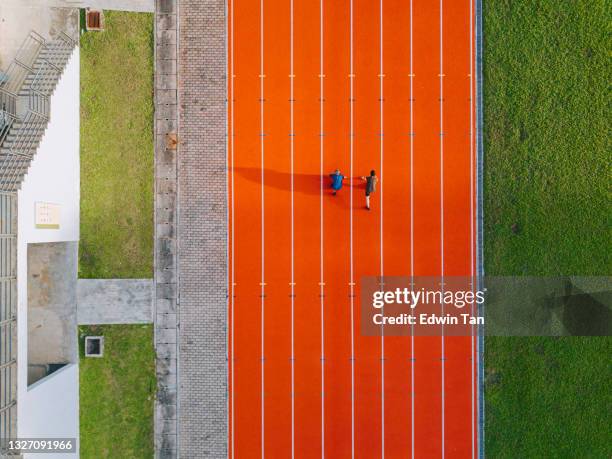 directement au-dessus du point de vue du drone, le fils père chinois asiatique s’alignant pour se préparer à courir sur piste et courir vers la ligne d’arrivée le matin au stade d’athlétisme à côté des gradins - father son challenge round two photos et images de collection