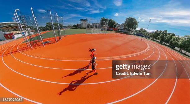 high angle fish eye side view 2 asian chinese female athlete running at woman's track at track and field stadium in the morning - championship round two stockfoto's en -beelden