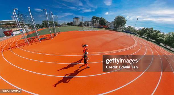 high angle fish eye side view 2 asian chinese female athlete running at woman's track at track and field stadium in the morning - running track stock pictures, royalty-free photos & images