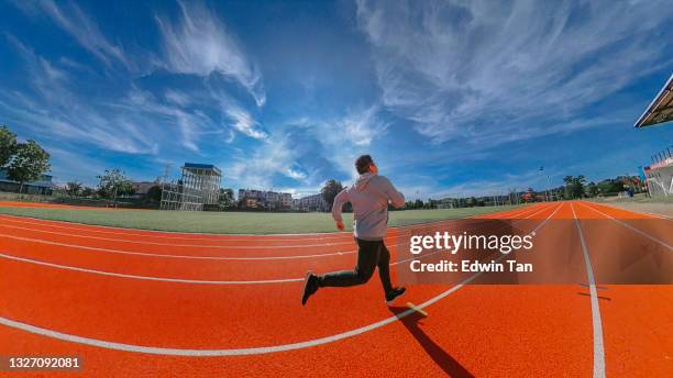 asian chinese mid adult man with hooded shirt long pants running funny at track and field stadium - sprint arena stock pictures, royalty-free photos & images