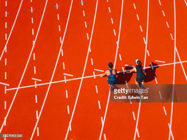 directly above drone point of view couple asian chinese athletes lining up getting ready starting line running at track and run towards finishing line in the morning at track and field stadium - forward athlete stockfoto's en -beelden