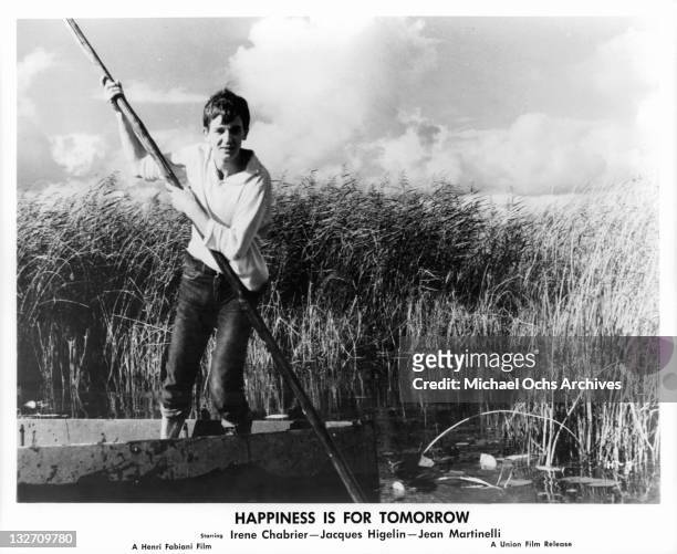 Jacques Higelin rowing raft through tall marsh in a scene from the film 'Happiness Is For Tomorrow', 1961.