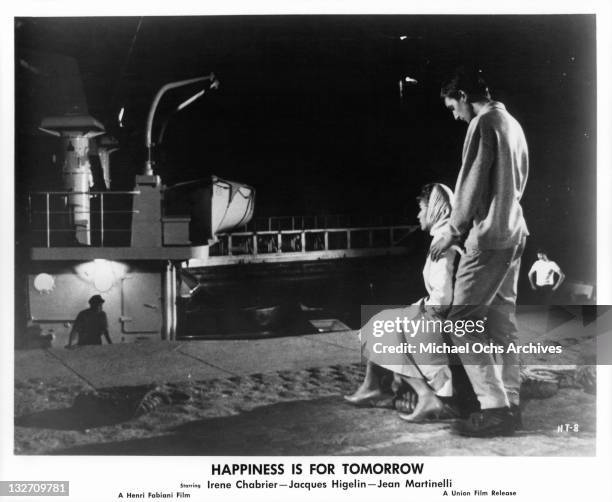 Irene Chabrier sitting while looking at ship, with Jacques Higelin touching her shoulders in a scene from the film 'Happiness Is For Tomorrow', 1961.