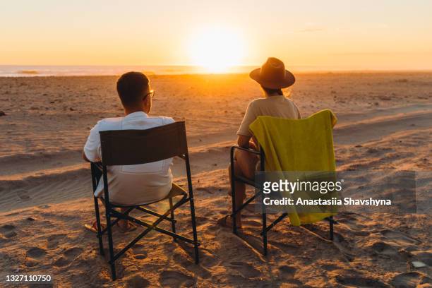 jeune femme et homme voyageur profitant du coucher de soleil pittoresque sur le camping de la plage en namibie - couché de soleil photos et images de collection