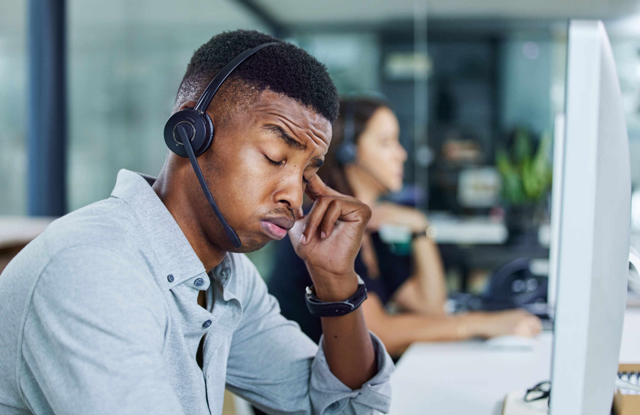 Shot of a young call centre agent looking tired in an office Shot of a young call centre agent looking tired in an office