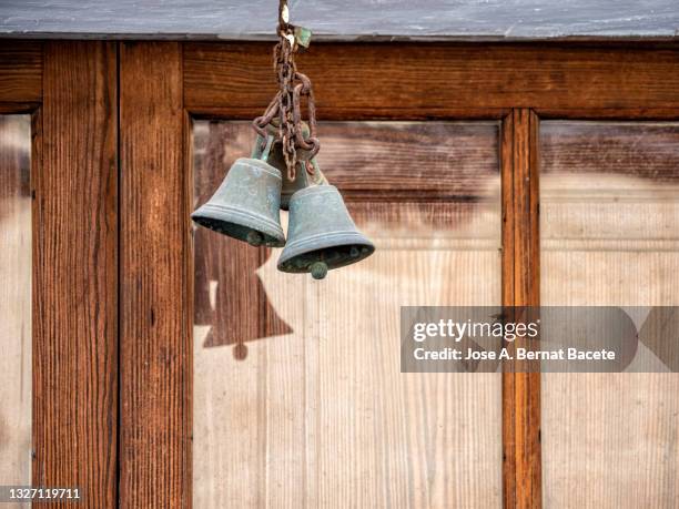 ancient door of wood in the street and a small metal bell with a chain. - campana de mano fotografías e imágenes de stock