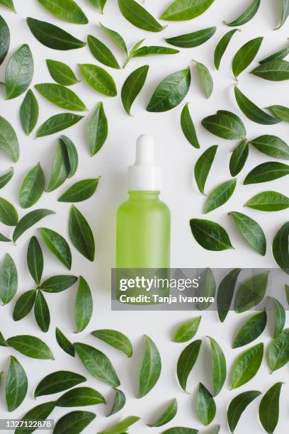 natural herbal serum in green glass bottle with a pipette and green leaves on white background. natural organic beauty product concept. flat lay, top view. - bottles glass top stock pictures, royalty-free photos & images