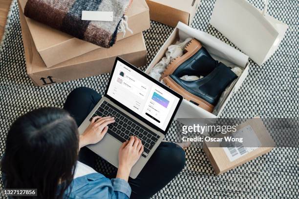 overhead view of young woman doing online shopping with laptop - shopping stock-fotos und bilder