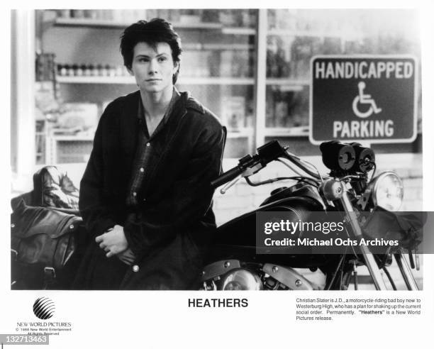 Christian Slater standing beside motorcycle in a scene from the film 'Heathers', 1988.