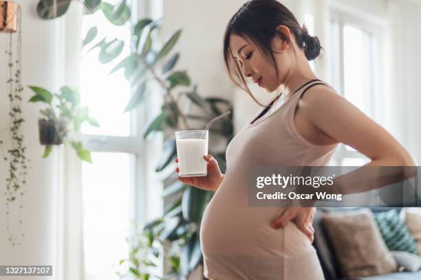 pregnant woman having a glass of milk at home - woman drinking milk stock pictures, royalty-free photos & images