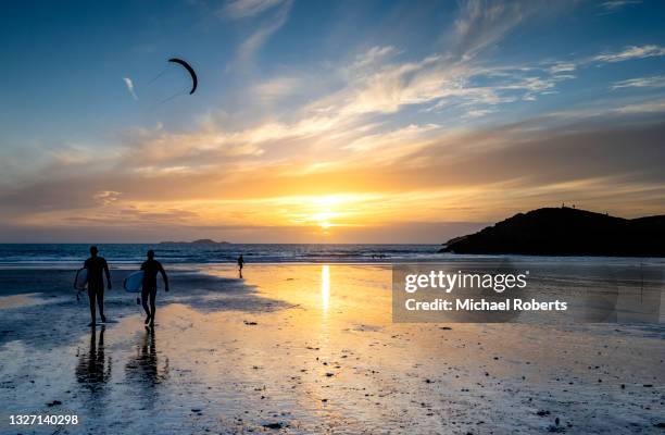 surfers on whitesands beach on the pembrokeshire coast path near st davids at sunset - st davids stock pictures, royalty-free photos & images