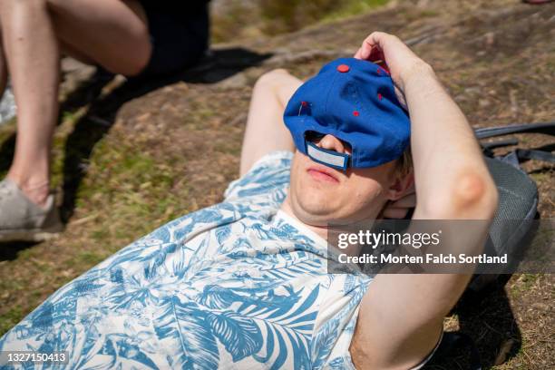 a young man relaxing outdoors - man sleeping with cap stock pictures, royalty-free photos & images