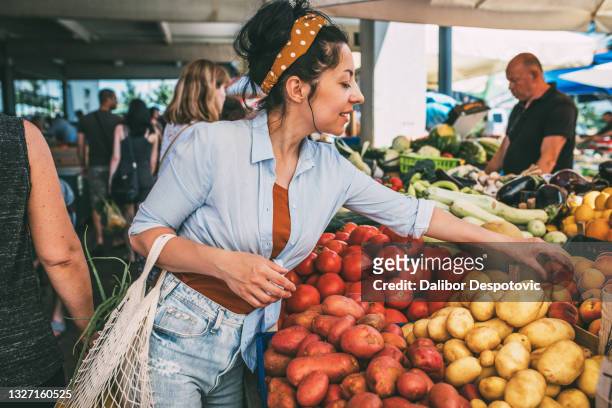 a young woman buys vegetables and fruits at the market . - buying stock-fotos und bilder