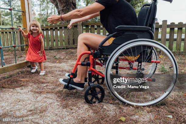 mother in a wheelchair with a disability playing with her little daughter in a park. - motion sickness stock pictures, royalty-free photos & images