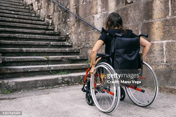 rear view of a young woman in a wheelchair looking at some stairs. - paraplégico imagens e fotografias de stock