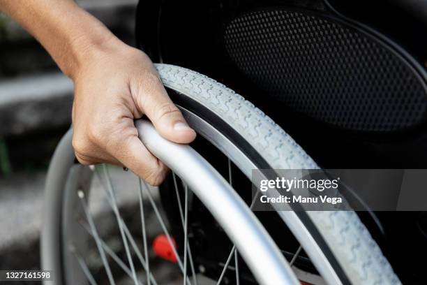 close-up of a woman's hand on the wheel of a wheelchair. - accessibilité aux personnes handicapées photos et images de collection