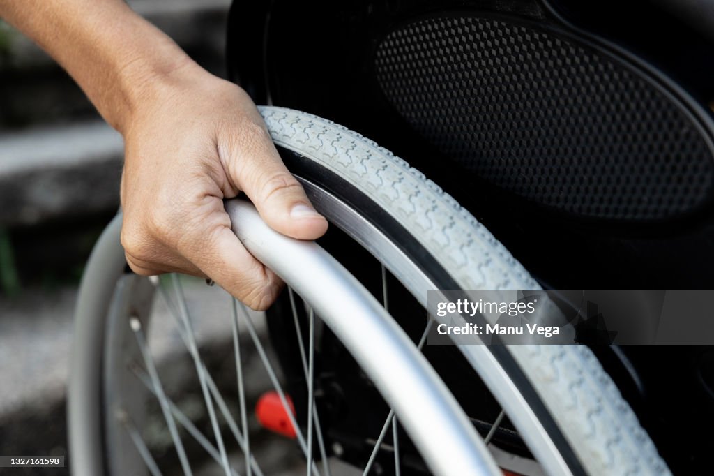 Close-up of a woman's hand on the wheel of a wheelchair.