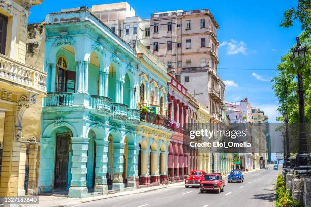 multicolored old american classic cars on street of havana against historic buildings - havana stockfoto's en -beelden