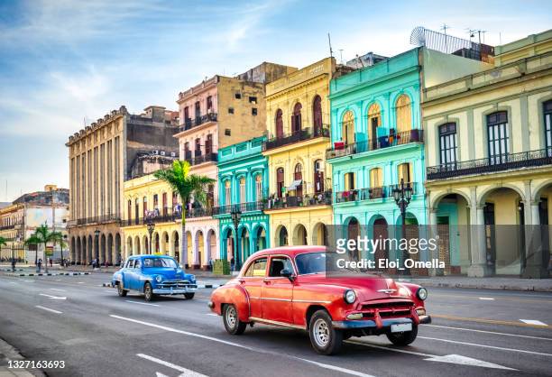 bunte oldtimer-taxiautos auf der straße von havanna gegen historische gebäude - cuba stock-fotos und bilder