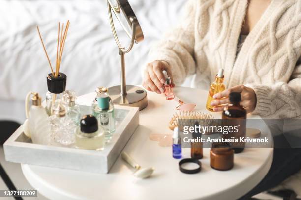 beauty products layed out on a small white round table, woman's hands holding bottles with serum - choosing perfume stock pictures, royalty-free photos & images