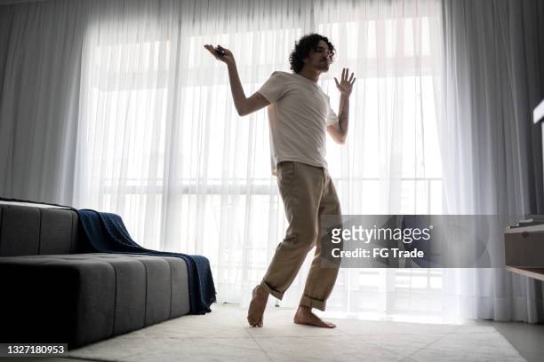 excited young man singing and dancing at home - guy dancing music dynamic stock pictures, royalty-free photos & images