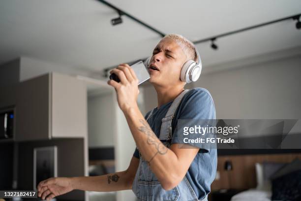 young man singing and dancing at home - man singing stockfoto's en -beelden