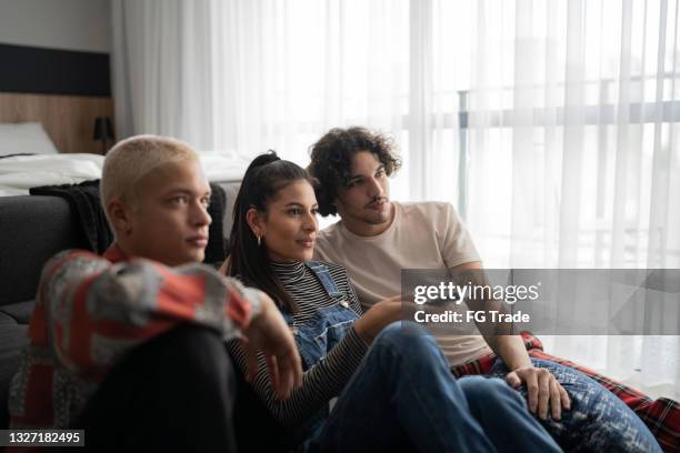 des amis qui regardent la télévision ensemble à la maison - television photos et images de collection