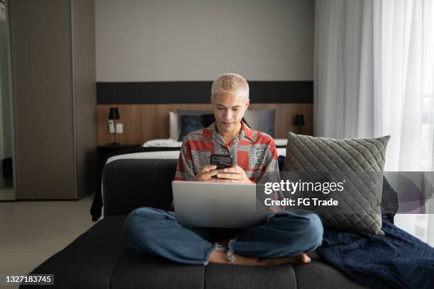 young man using smartphone and laptop at home - scanner stock stock pictures, royalty-free photos & images