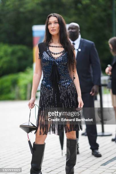 Bella Hadid wears a black pearls necklace from Louis Vuitton, a black sequins / glitter shiny sleeveless short dress with knot on the chest and tulle...