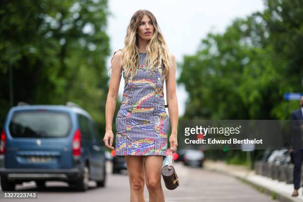 Veronika Heilbrunner wears a navy blue and white striped buttoned short dress with multicolored print pattern, a gold ring, a brown monogram in...