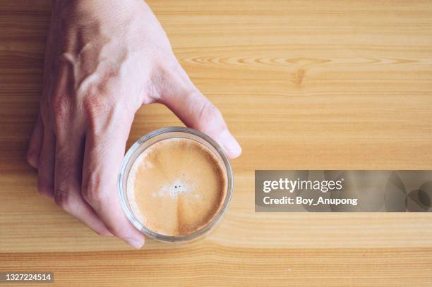 table top view of someone hand holding a cup of espresso coffee on wooden table. - crema stock pictures, royalty-free photos & images